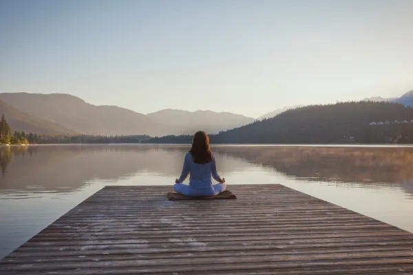 Image of a person connecting with nature, such as hiking in a forest, sitting by a lake, or gardening.