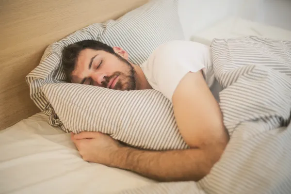 Image of a person sleeping soundly in a comfortable bed, with a focus on the brain and its functions.