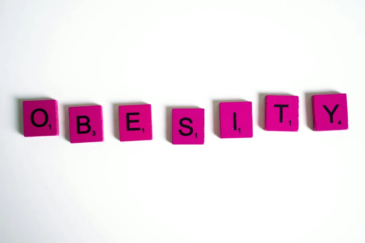 Bright pink letter tiles spell out the word "OBESITY" on a white background, symbolizing the hidden neurological and spiritual weight that excess weight can carry—a visual cue for the blog’s message on brain health, emotional peace, and God’s renewal.