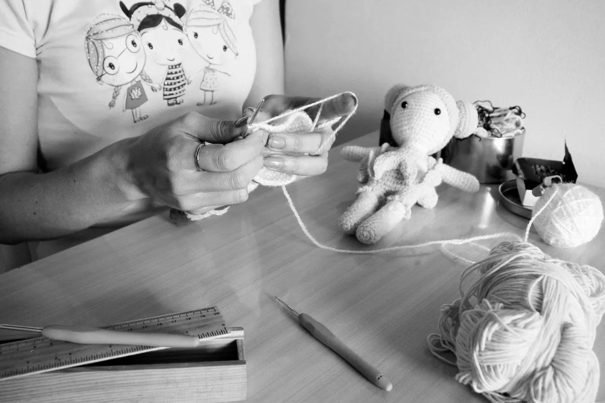 Black and white image of a woman crocheting a stuffed animal at a tidy desk, symbolizing how learning a new hobby can support brain health, reduce stress, and reflect God's design for mental renewal.