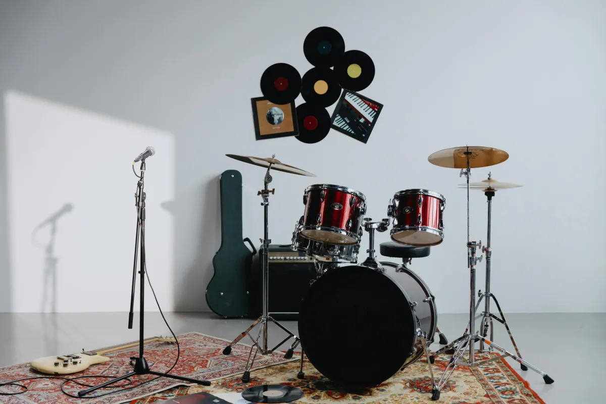 A music studio setup featuring a red drum kit, guitar, microphone, and vinyl records on the wall. The scene suggests creativity, musical expression, and the brain-boosting power of learning an instrument at any age.