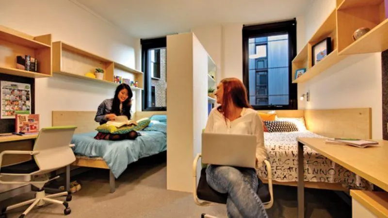 “Student dorm room with books and luggage representing housing for international students in the U.S.”
