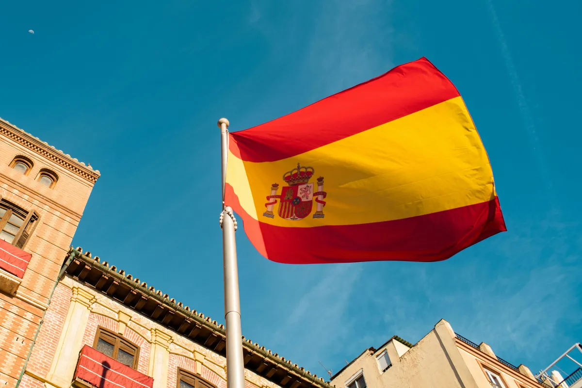 Spanish flag above a university building symbolizing PhD scholarships in Spain.