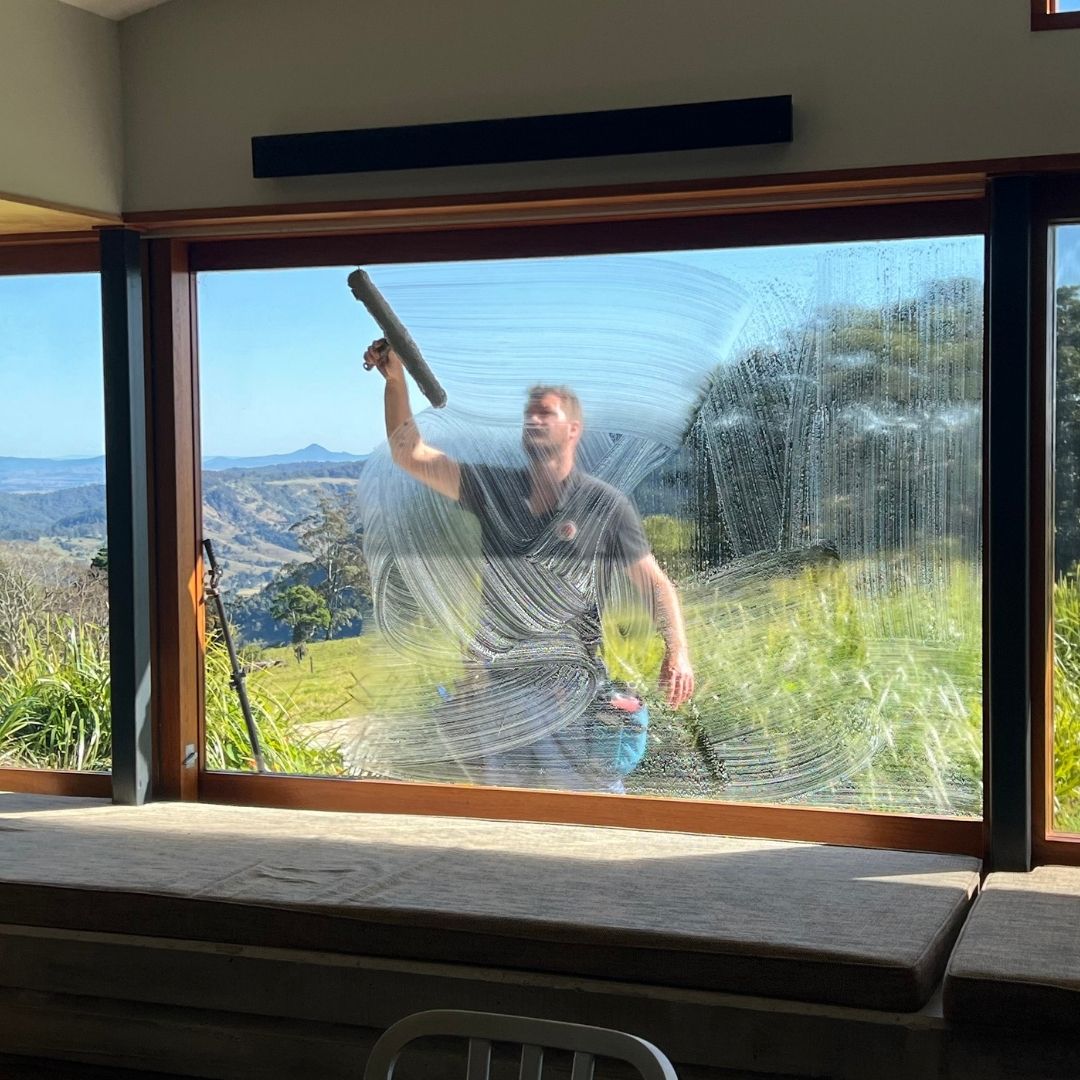 Professional window cleaner squeegeeing glass at a Gold Coast home