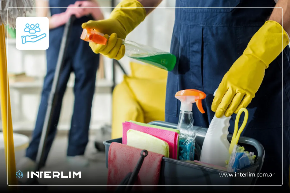 Mujer profesional de limpieza limpiando una mampara de cristal en una oficina.