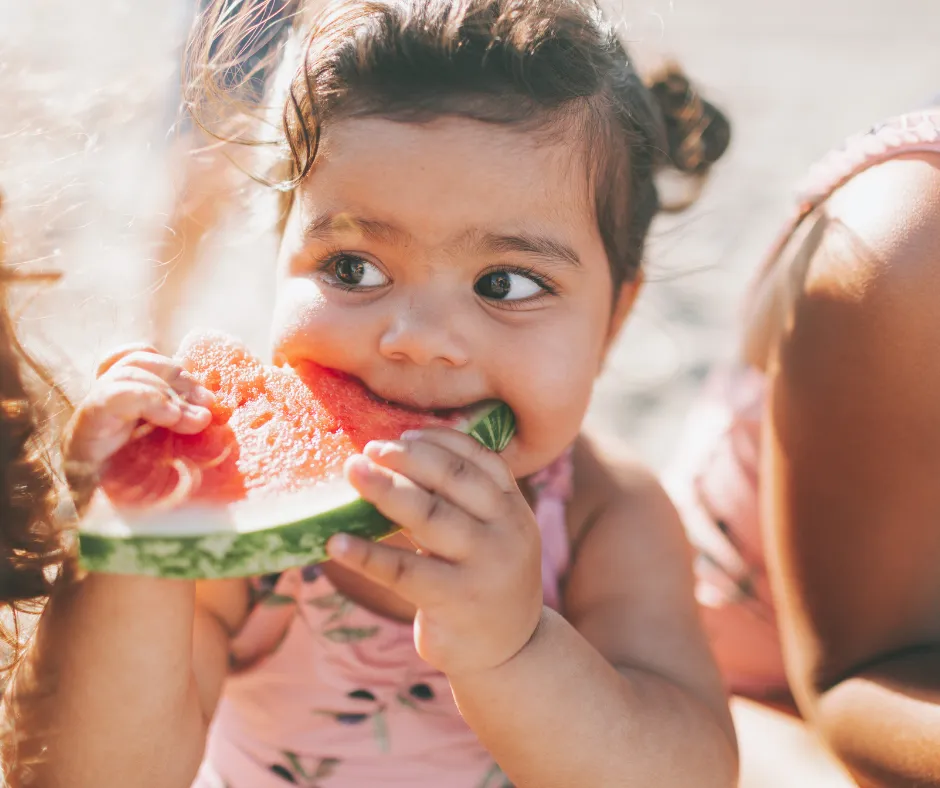 toddler girls eating fruit with curiosity