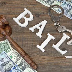 Bail concept with gavel, handcuffs, cash, and the word “BAIL” on a wooden surface.