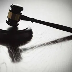 Judge’s gavel casting a shadow on a wooden surface.