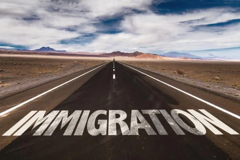 Open road stretching into the distance with the word “IMMIGRATION” painted on it.