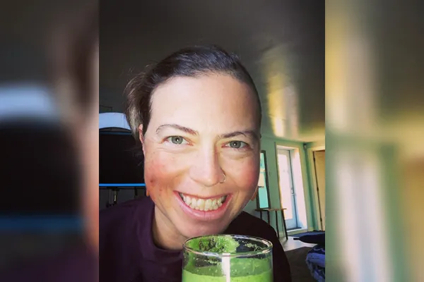 woman smiling holding green juice jules hare holding green juice