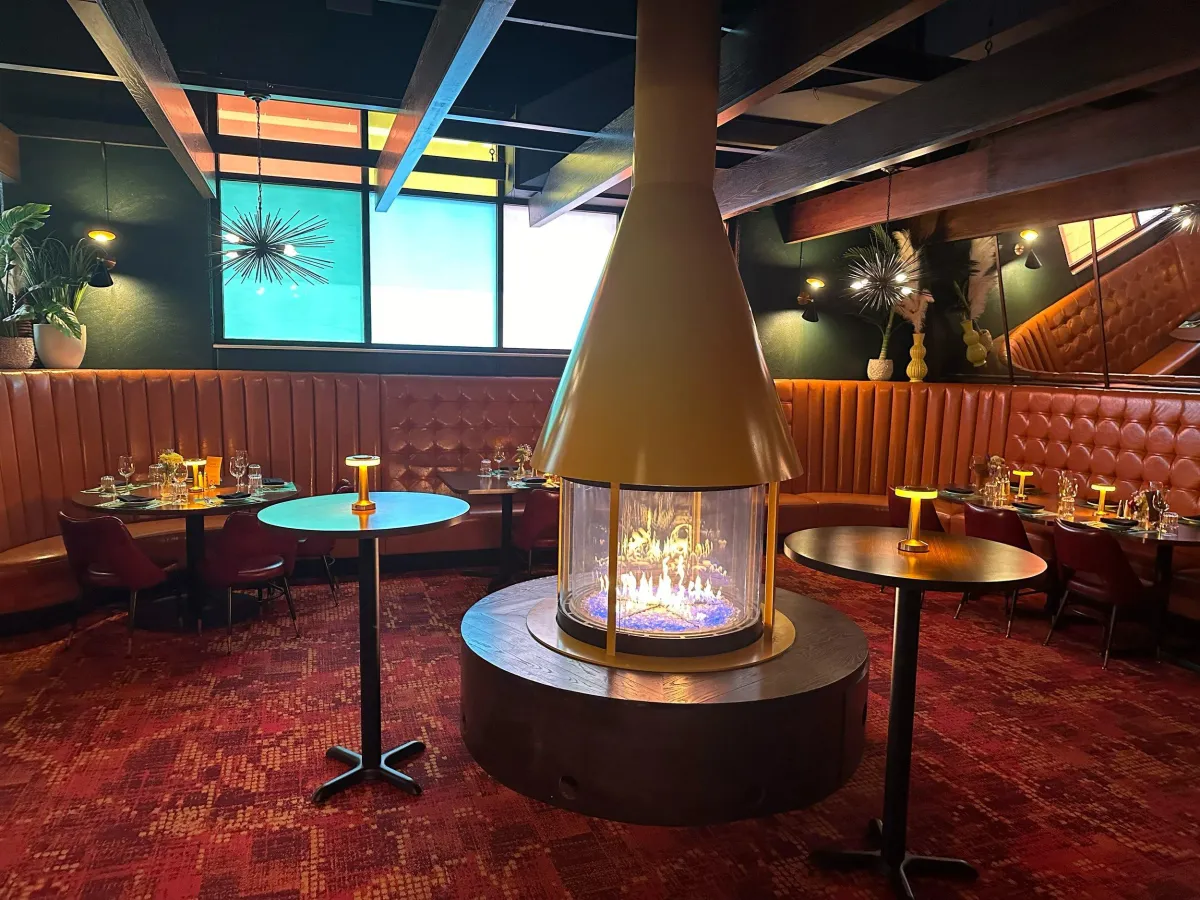 a circular mango-colored gas fireplace sits in the middle of high-end restaurant