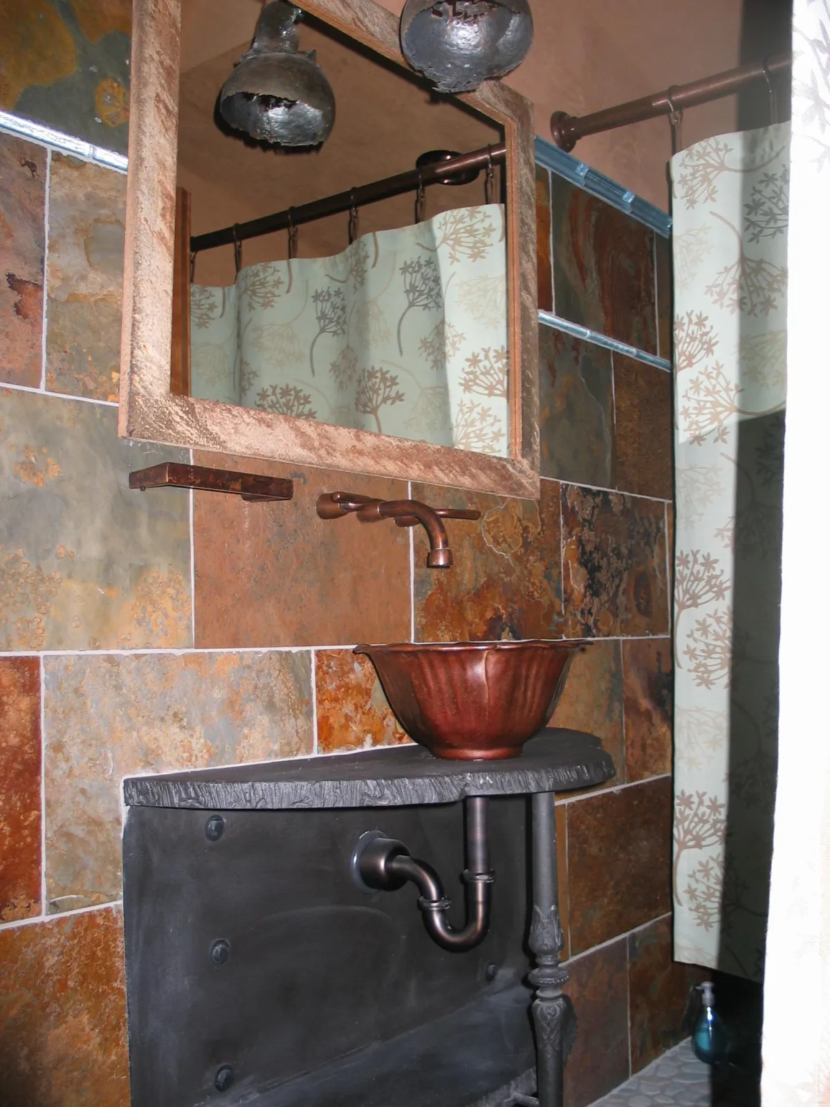 rough torch cut edge on thick piece of steel with an antique cast iron leg for a bathroom counter and custom cast iron light