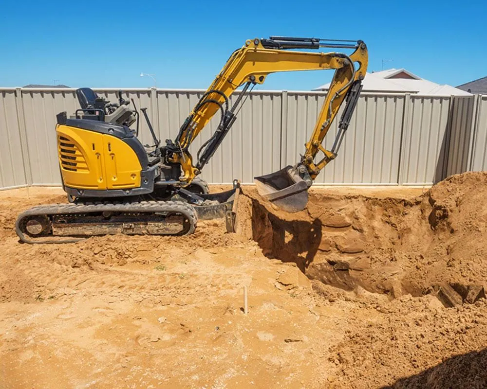Yellow mini excavator digging in a suburban backyard in West Michigan