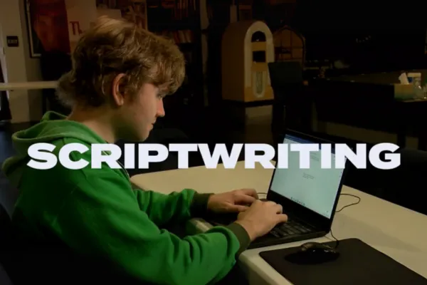 Students of diverse abilities collaborating on a script in an inclusive classroom at JDS Creative Academy, with writing materials, storyboards, and cameras visible.