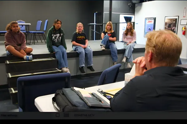 Students performing Frozen Jr. on stage with Arendelle castle backdrop and sparkling snow effects