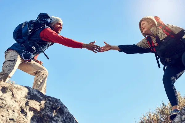 Happy hikers reaching for each other's hands.