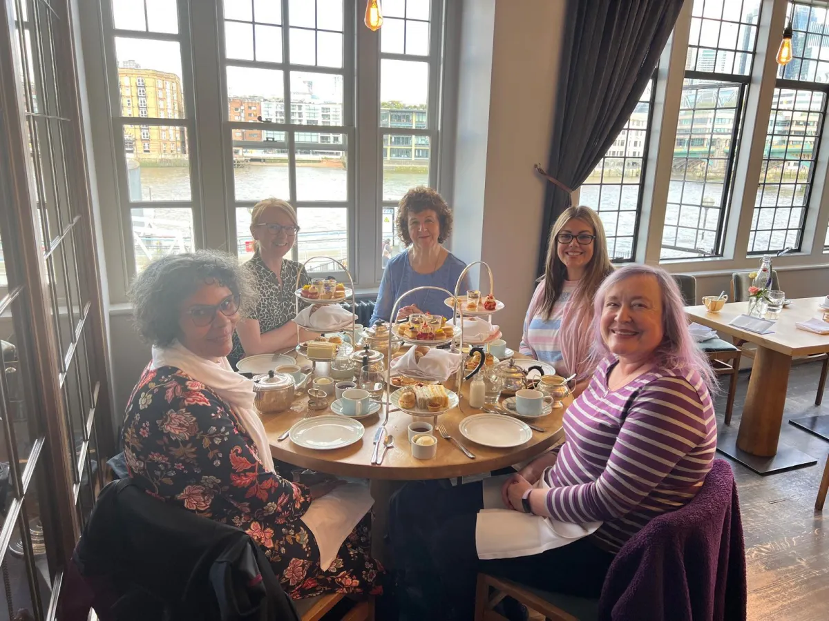 Women enjoying afternoon tea together at a restaurant by the window.