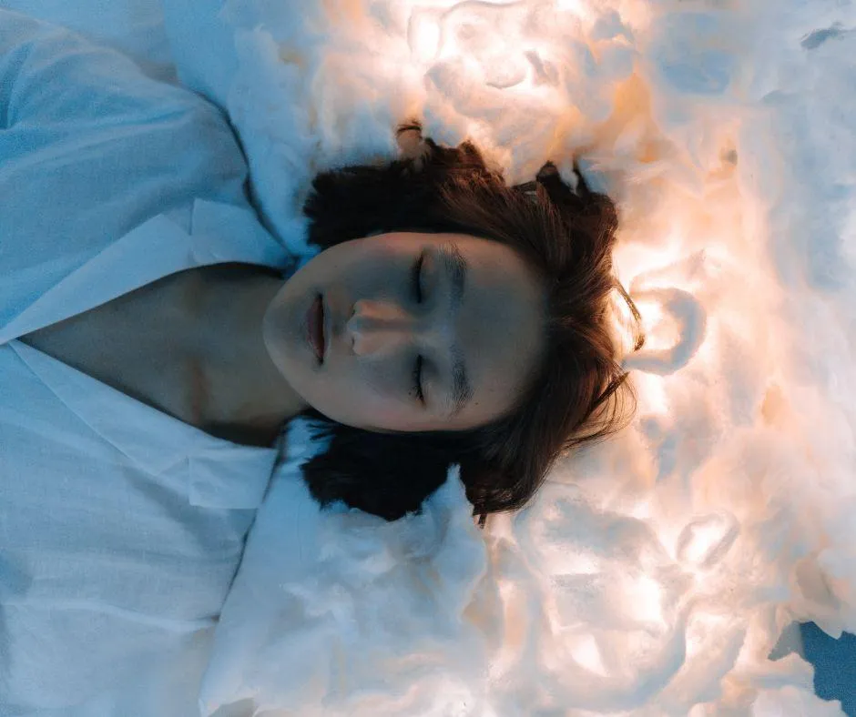 Woman in a peaceful, dreamlike state floating in clouds representing emotional healing through ketamine assisted psychotherapy