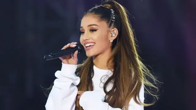 Ariana Grande performing live on stage, holding a microphone during a viral moment that highlighted her live vocals.