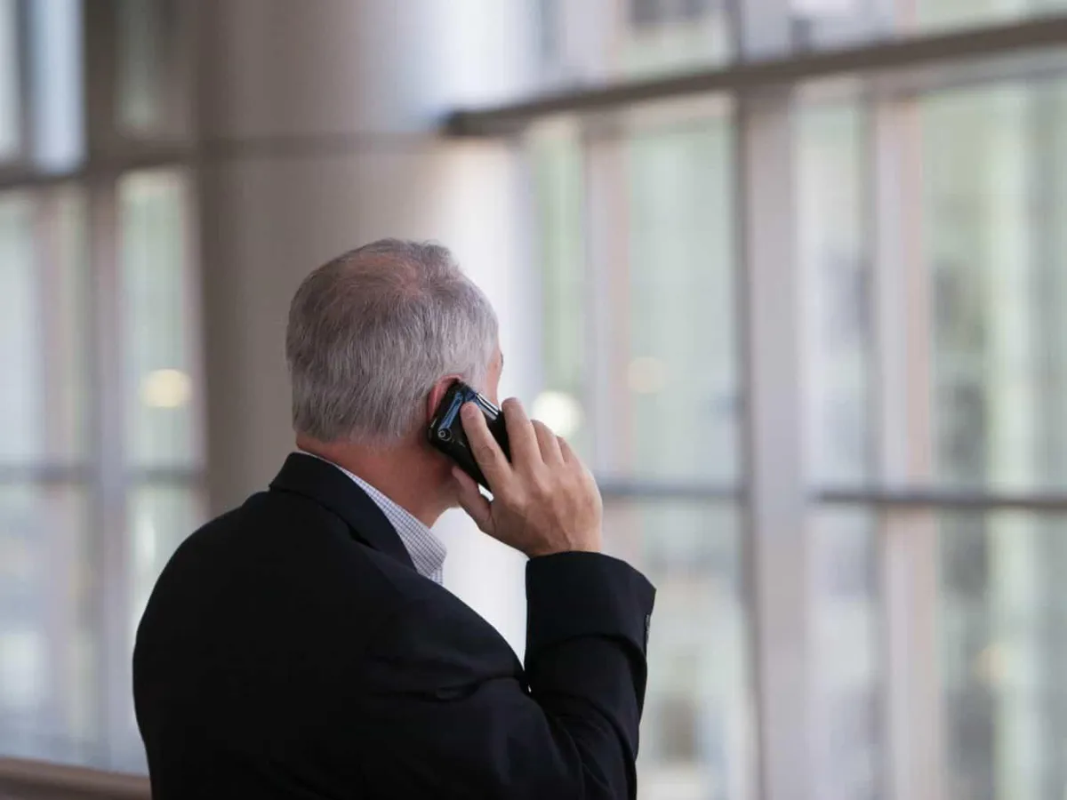 Businessperson consulting with a legal advisor on the phone while reviewing a contract.