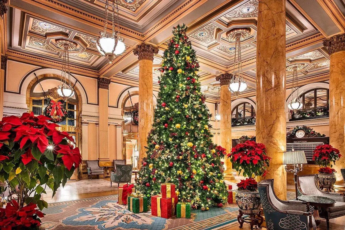 Grand hotel event space styled with holiday decor, Christmas trees, gold accents, and cheerful seasonal atmosphere.