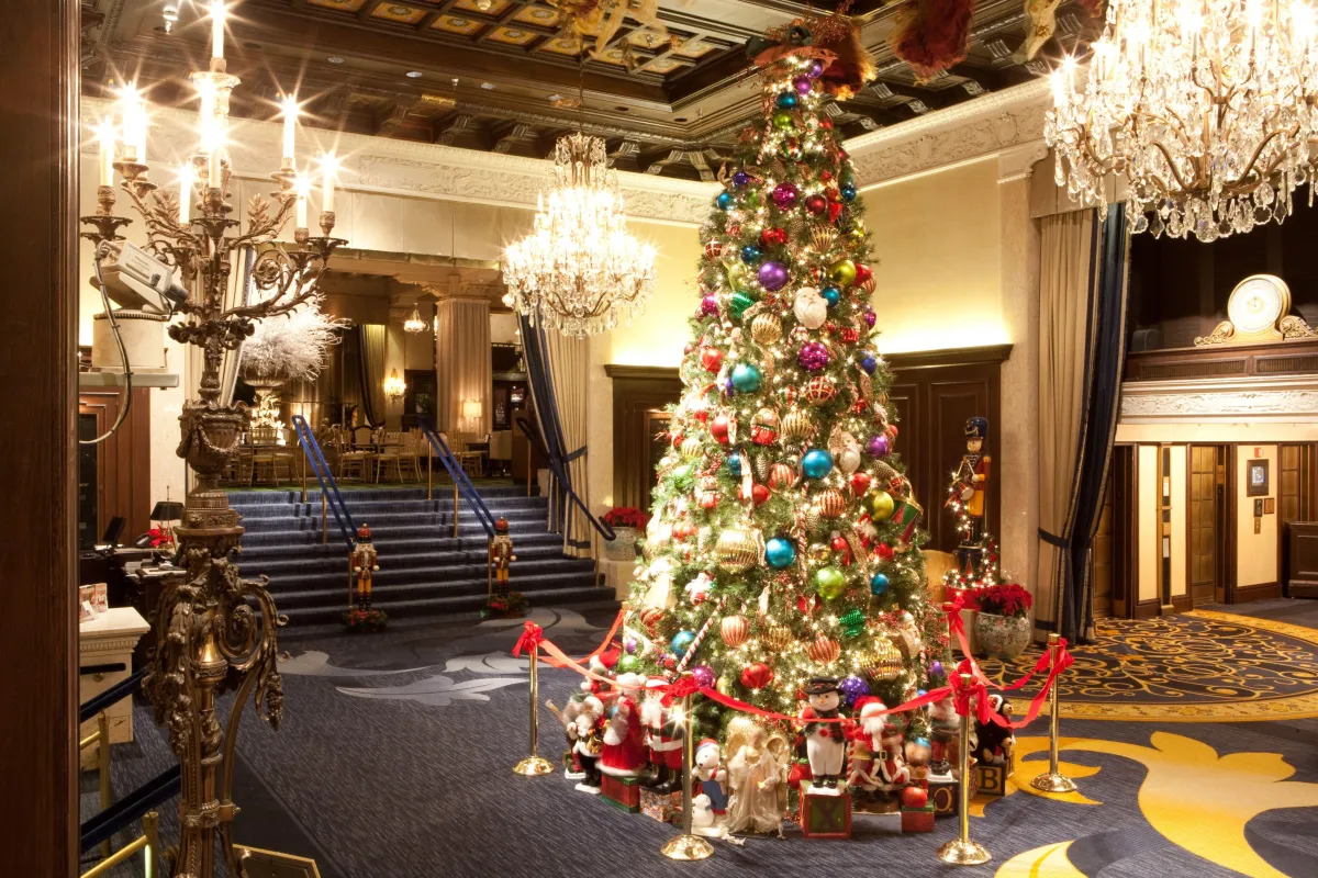 Luxurious hotel lobby decorated with traditional Christmas decorations, garlands, ribbons, glowing lights, and festive warmth.