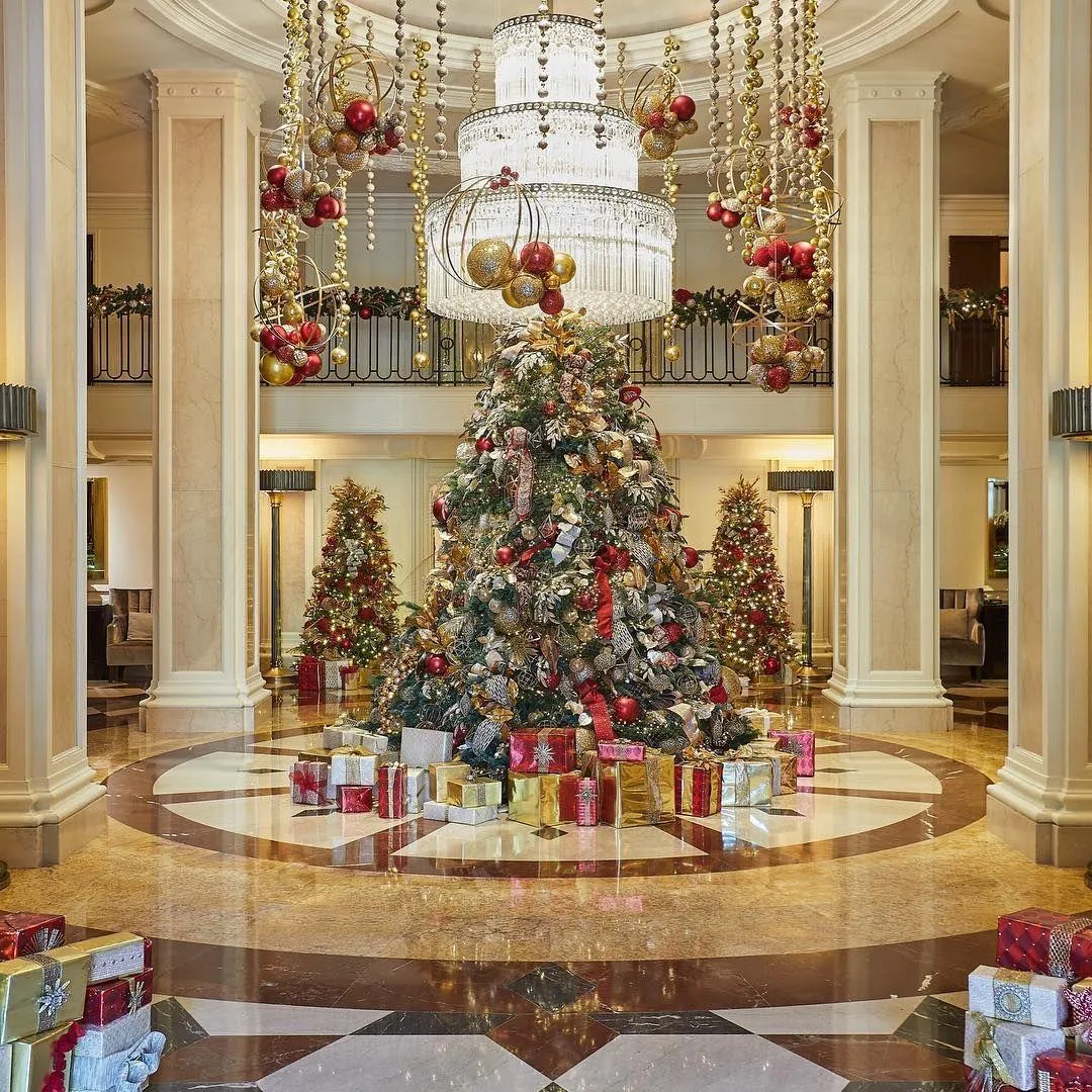 Hotel interior featuring traditional holiday decor with red ribbons, golden baubles, and lush green Christmas garlands.
