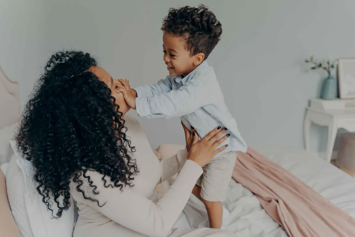 The mother is joyfully engaging and playing with her kids in the morning.