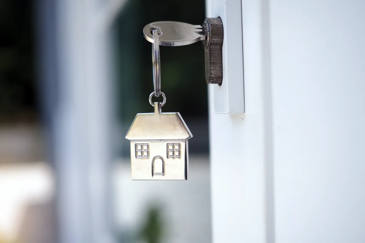 An open front door with a house shaped key
