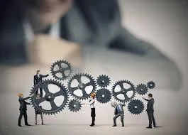 Illustration of business professionals working together to turn interconnected gears, symbolizing the importance of having a disaster recovery team to keep business operations running smoothly during and after a crisis.