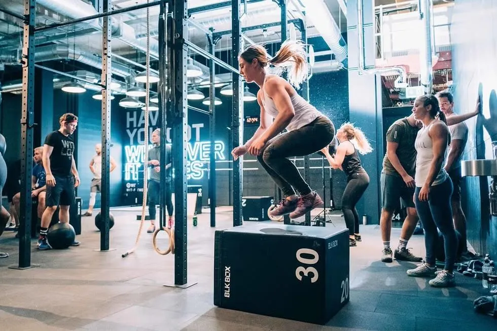 Adultes s’entraînant dans un centre d’entraînement fonctionnel, encadrés par un coach, illustrant des fondations solides pour la santé en 2026