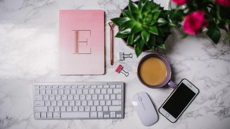 Notebook, keyboard, cup of tea, iPhone and plant on a desk
