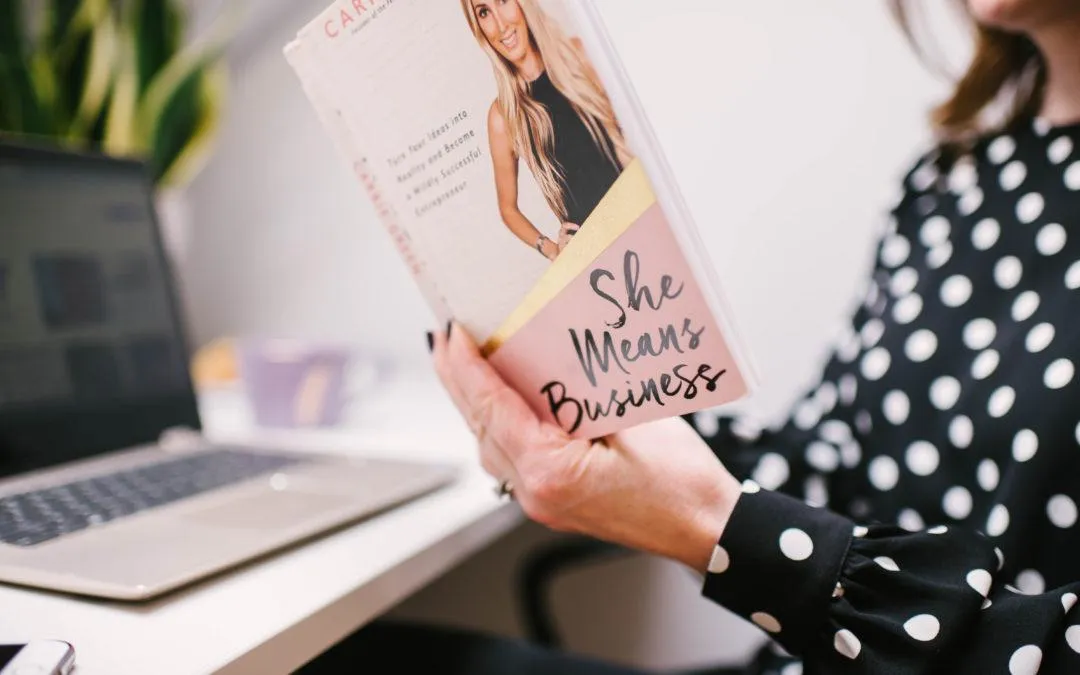 Hands holding a book titled 'She Means Business'