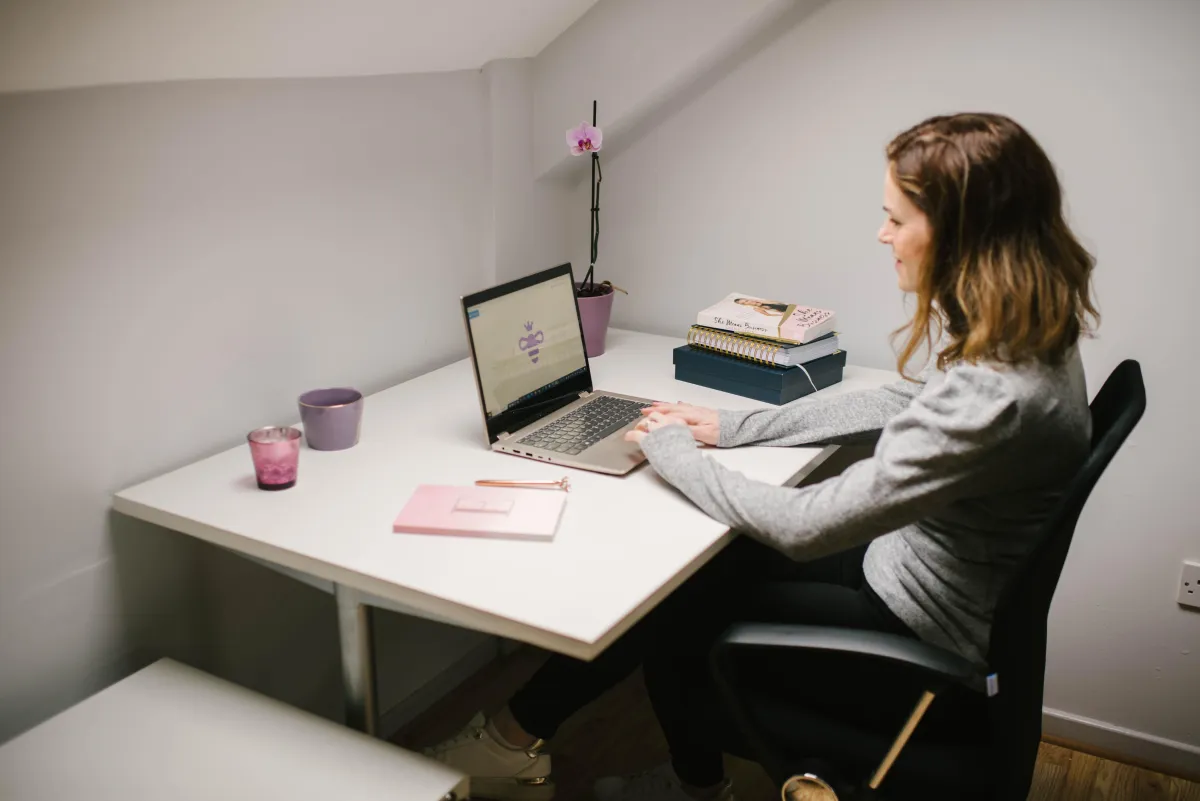 Eve sitting at a desk typing on a laptop