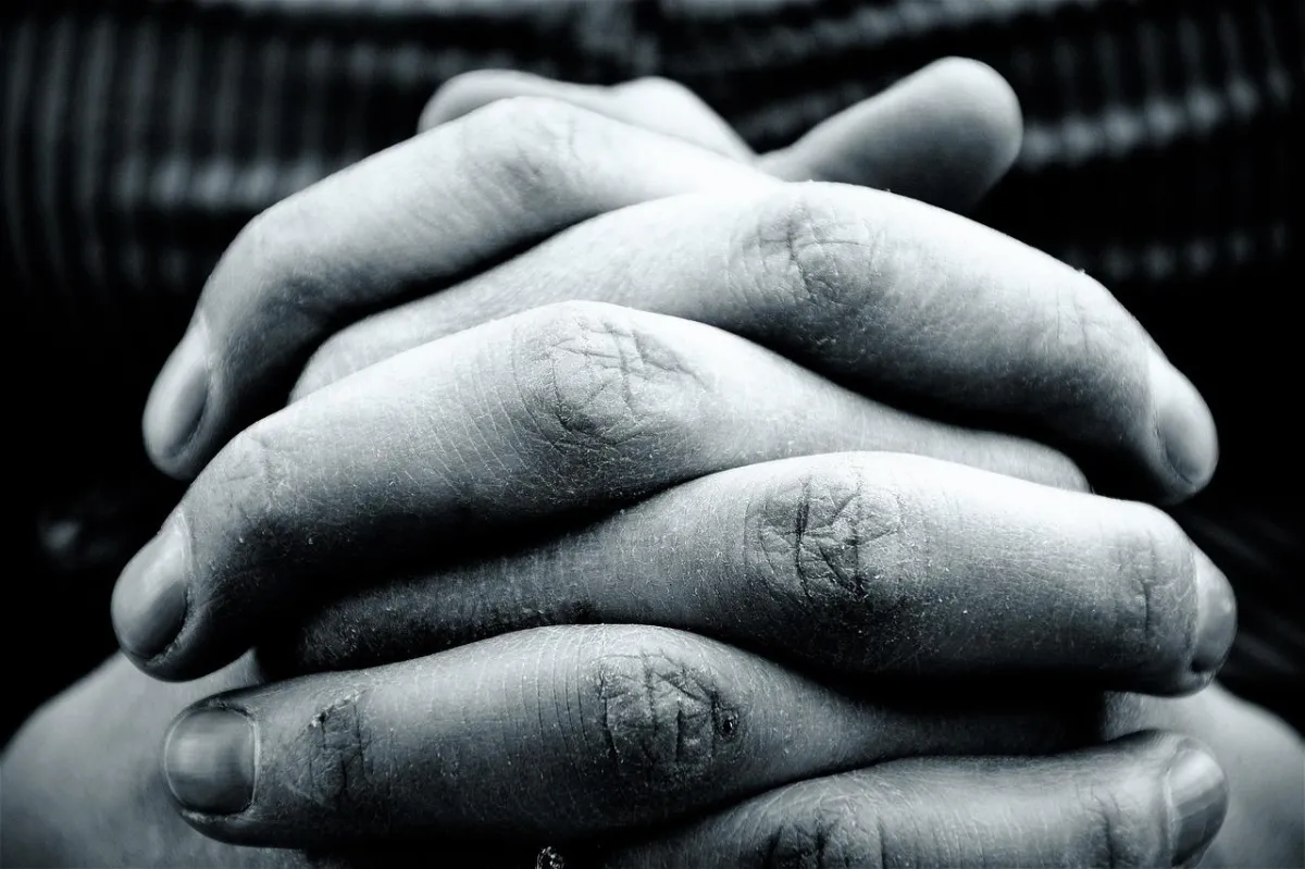 Close-up of clasped hands in prayer, symbolizing faith, surrender, and trust in God during difficult times.