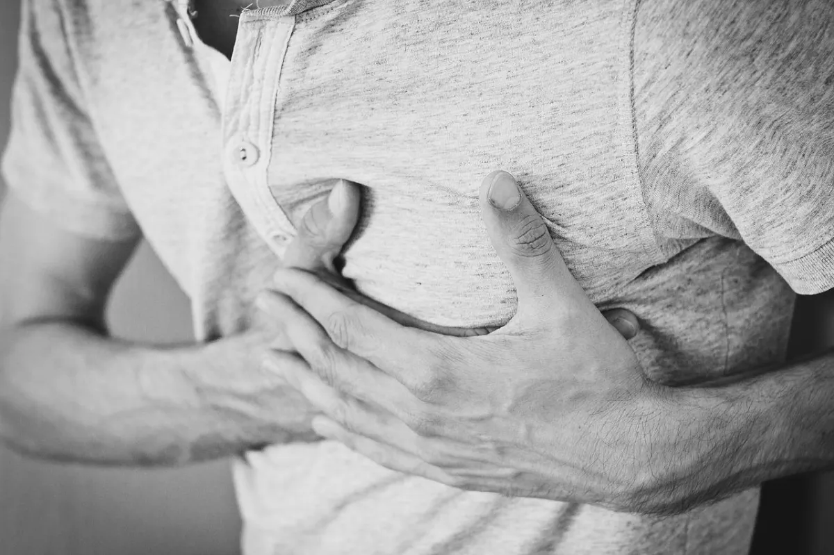 Black and white image of a man clutching his chest in emotional or physical pain, symbolizing inner hurt, heartbreak, or the need for healing and forgiveness.