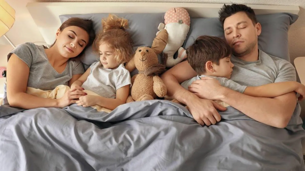 A family with two children sleeping in a bed