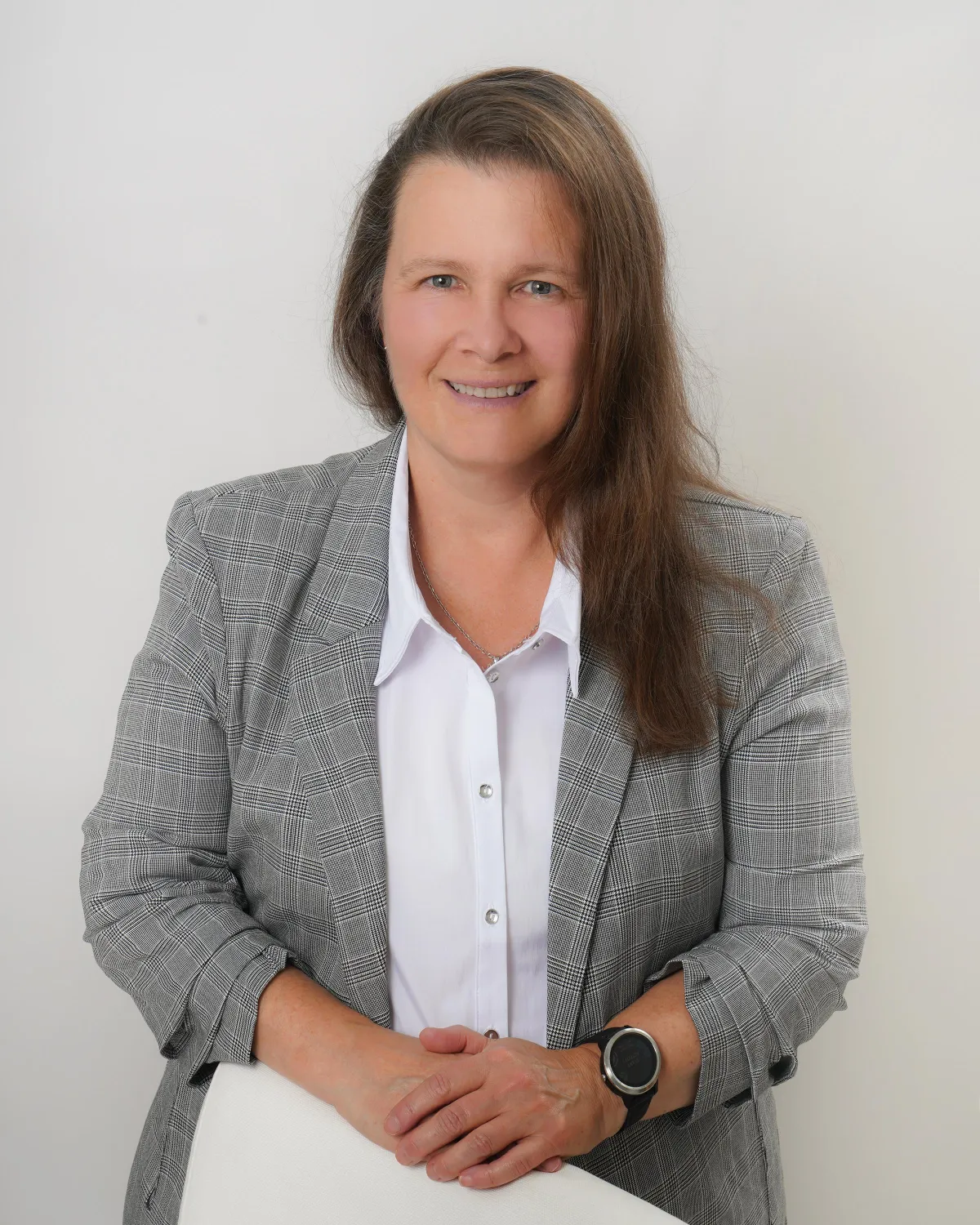 Woman in a green blazer sitting in front of a white background