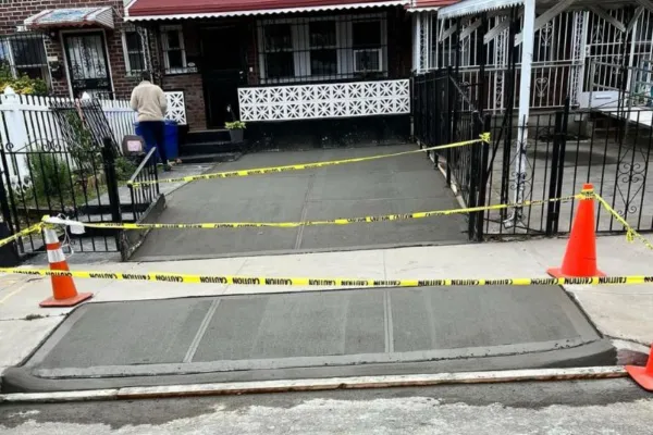Sidewalk demolition zone with exposed gravel, “Sidewalk Closed” sign, orange cones, and safety tape; preparation for new concrete slab in urban area. Queens, New York