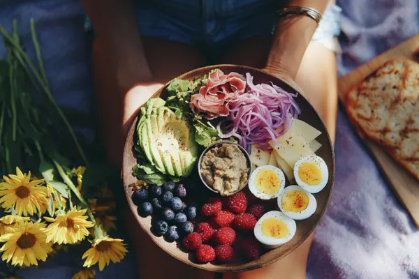 plate of summer foods held by a lady on a blanket