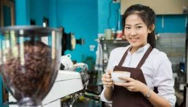Smiling barista offering a cup of coffee