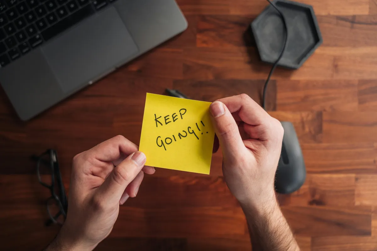 A post it note that says keep going