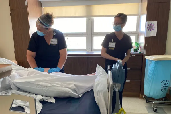 two massage therapists working with a patient in a hospital room