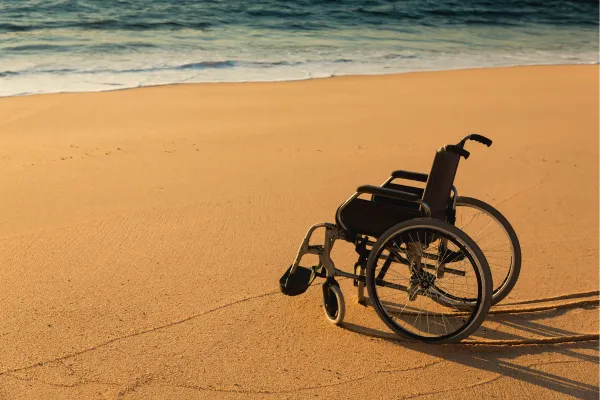 a wheelchair sits on the beach near the ocean