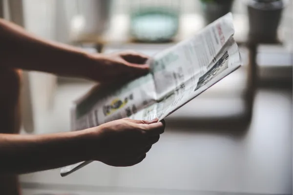 a person reading a newspaper in front of a window