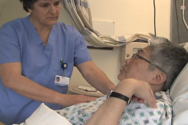 a massage therapist helping an elderly woman in a hospital bed