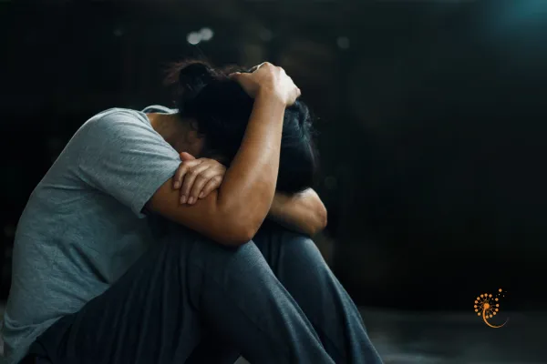 a person sitting on the floor with their head in their hands