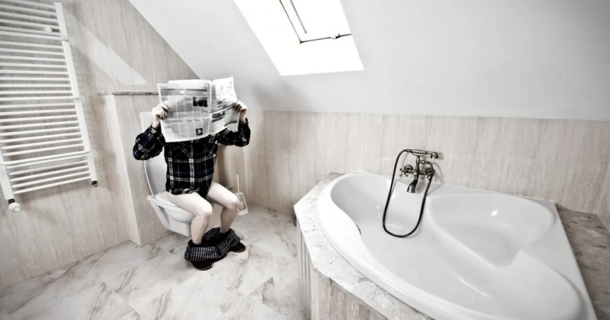 man reading newsletter in bathroom.