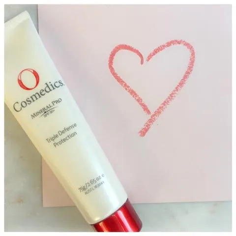 O Cosmedics SPF laying next to a drawn heart on pinkn paper