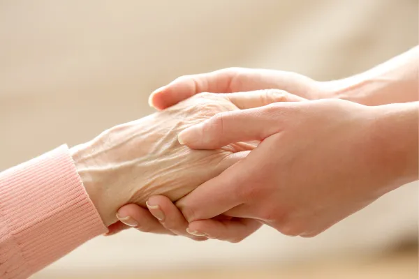 Close up of a caregiver holding an elderly persons hand with compassion support and senior care